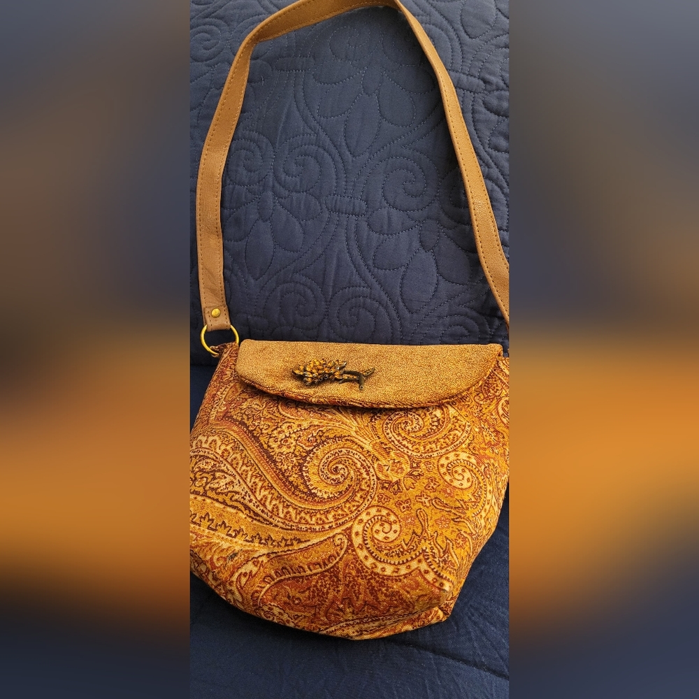 Boutique paisley bag with floral pin adornment.